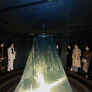 A group of people standing around a large green object Description automatically generated