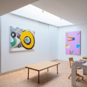 A room with art paintings and a table Description automatically generated