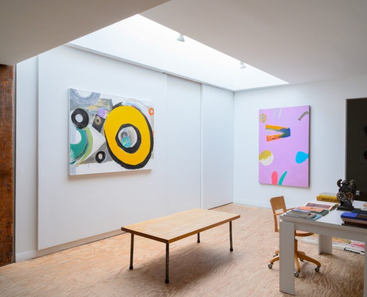 A room with art paintings and a table Description automatically generated