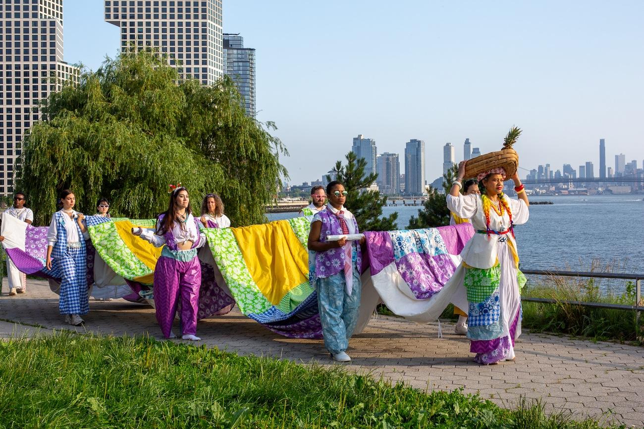 Jodie Lyn-Kee-Chow and her collaborators parade into Hunter’s Point South Park in “The Picnic: Harvest of the Soft Sweet Sound.” Photographed by Yann Chashanovski. Courtesy of Flux Factory.